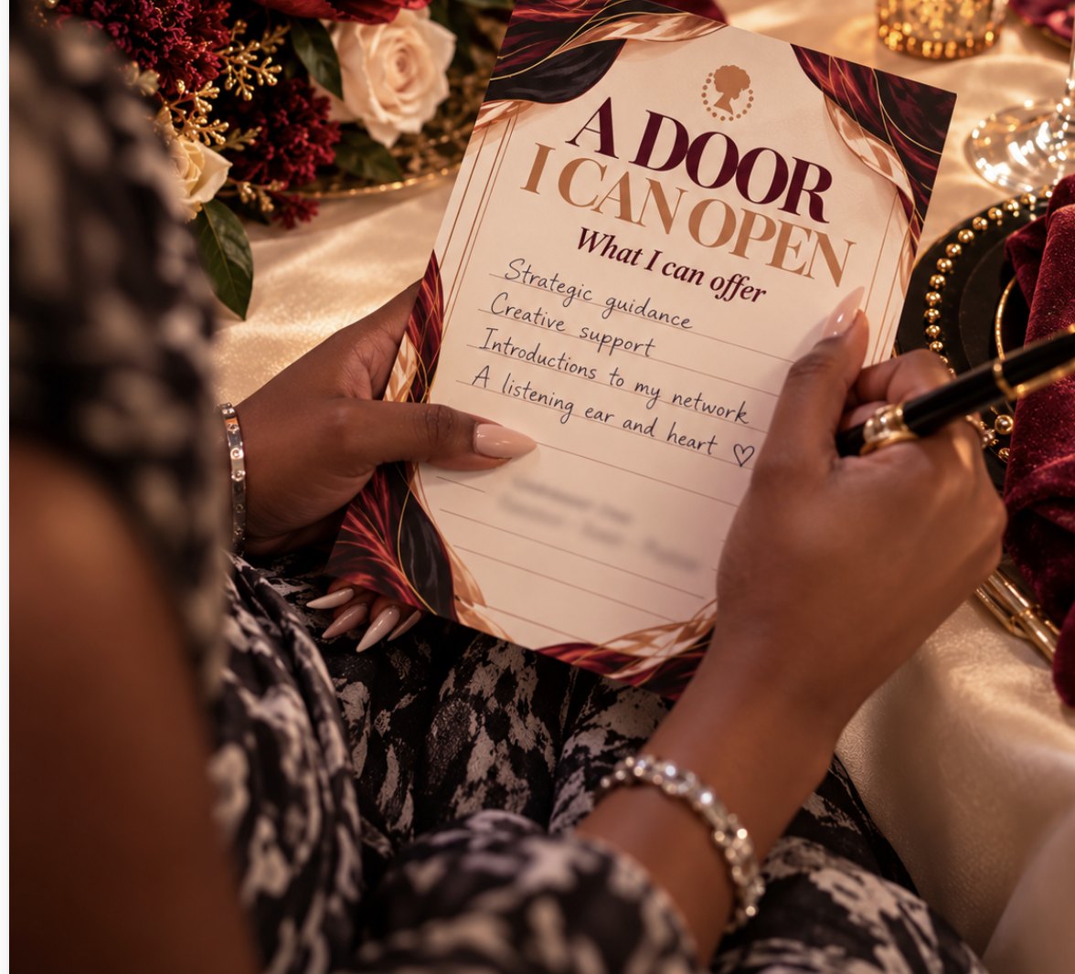 A guest’s hands holding an ‘A Door I Can Open’ card filled in by hand, a black pen in one hand, at a table of florals and gold.