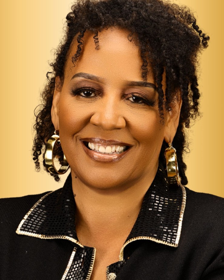Portrait of Dr. Cheryl Pruitt, smiling, against a warm gold background.