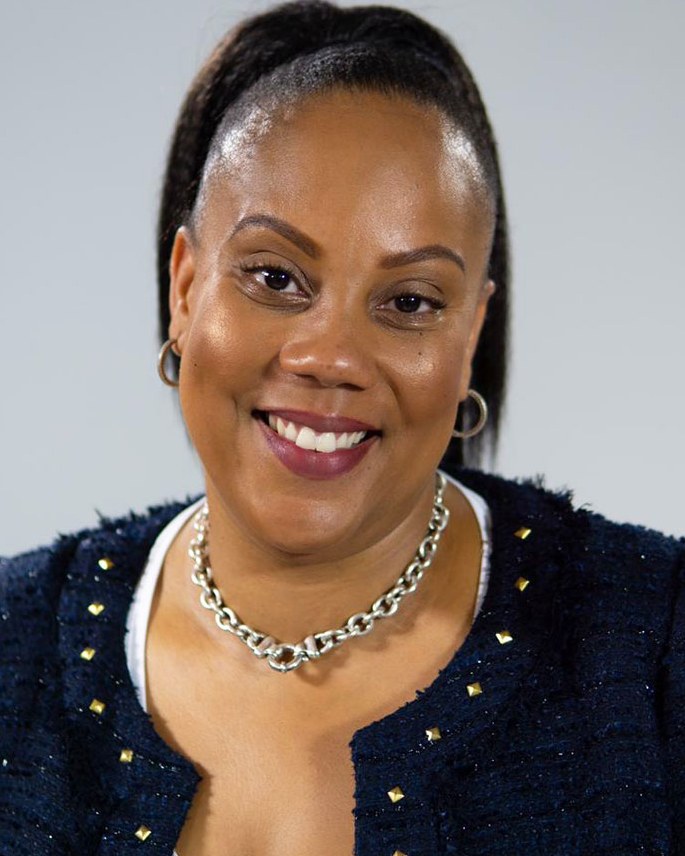 Portrait of Natalia Nicholson, smiling, in a navy tweed jacket and silver chain necklace.